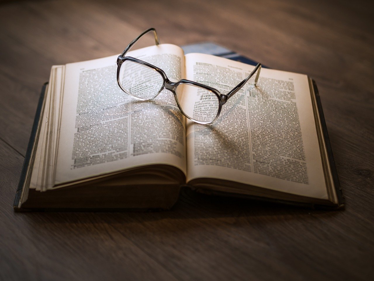 Livro aberto com óculos sobre as páginas